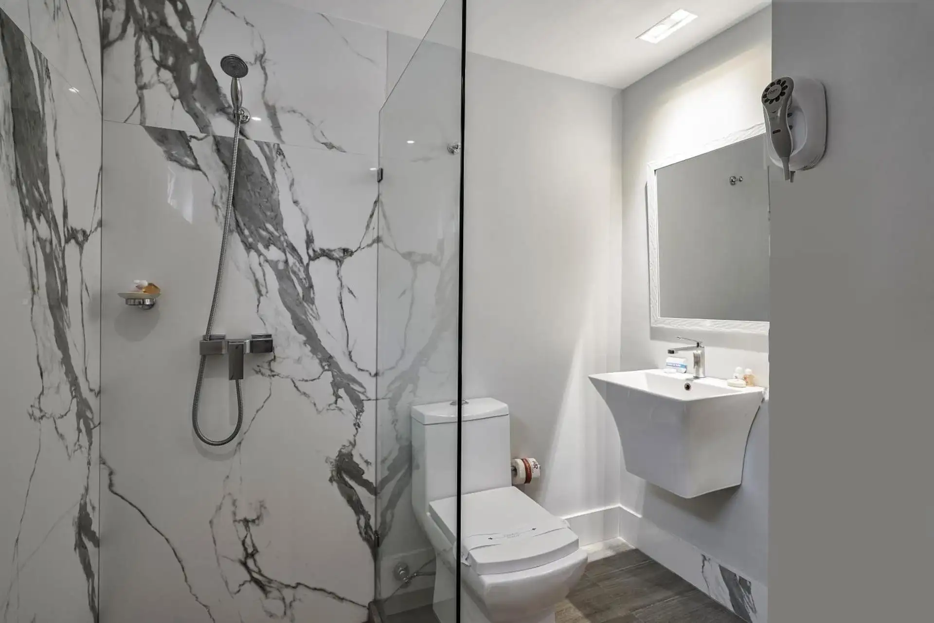 Baño con ducha y mármol blanco en el Hotel Riazor
