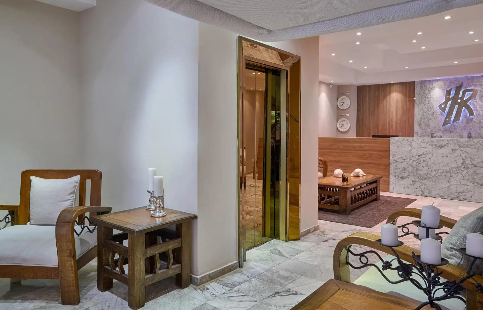 Lobby del Hotel Riazor con palmas, sofás de madera y suelos de mármol